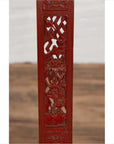 Close-up of red lacquered wood panel with carved floral and bird motifs on antique folding chair.
