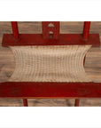 Red lacquered wood folding chair with footrest and fabric, on wood floor.