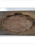 Brown wooden antique Chinese rice mold with carved lotus symbol and Fu bat motif, close-up of detailed design.
