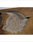 Brown wooden Chinese rice mold with carved koi fish and lotus blossom designs, close-up view on plain background.