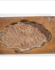 Brown antique wooden Chinese rice mold with carved fish and floral medallion motifs, close-up view.