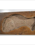 Close-up of antique Chinese rice mold made of wood, featuring fish and floral medallion carved motifs.