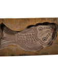 Brown wood antique Chinese rice mold in fish shape for sweets or pastries, close-up on surface.