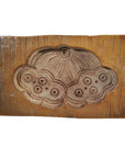 Brown antique Chinese wooden rice mold with carved cloud and floral designs, close-up view on plain background.