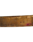 Close-up of a rectangular, worn wooden Chinese rice mold with scratches and a small purple stain on one end.