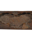 Brown wood antique Chinese rice mold with carved floral design, three flowers, leaves, and cloud-shaped border, close-up.