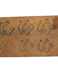 Brown wooden antique Chinese rice mold with 18 plum blossom cavities, long format, close-up on a plain background.