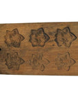 Brown antique wood rice mold with eighteen plum blossom cavities, long rectangular shape, close-up on plain background.