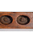 Brown wooden antique Chinese rice mold with two round fluted impressions, close-up view.