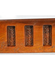 Close-up of three antique wooden Chinese rice mold panels arranged in a row on a wooden surface.