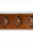 Brown antique Chinese rice mold with three repeating diamond-shaped floral patterns, wood material, close-up view.