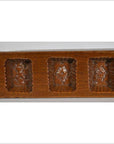 Close-up of antique wooden Chinese rice mold with ornate rectangular sections, shown on a plain surface.