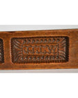 Close-up of antique brown wooden Chinese rice mold with carved initials “JHMW” and intricate leaf pattern.