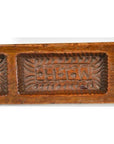 Close-up of a carved wooden antique Chinese rice mold with geometric and leaf patterns.