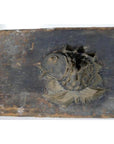 Brown wooden antique Chinese rice mold with carved fish, showing detailed scales and fins, on rectangular board, close-up.