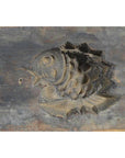 Close-up of dark, weathered antique Chinese rice mold with detailed fish carving, wood surface visible.