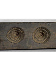 Close-up of a brown antique Chinese wooden rice mold with coin, fish, and diamond cavities on a weathered wood surface.