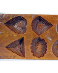 Brown wooden antique Chinese rice mold with geometric eight-shape design, close-up on plain surface.