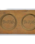 Close-up of light wood antique Chinese rice mold with three round character stamps.