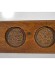 Close-up of brown antique wooden Chinese rice mold with five leaf bud impressions and a symmetrical floral motif carving.