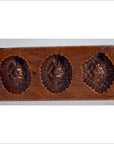 Close-up of antique Chinese rice mold, brown wood, with seven rectangular mixed-motif cavities.