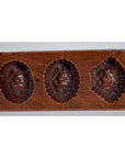 Close-up of antique Chinese rice mold, brown wood, with seven rectangular mixed-motif cavities.