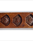 Brown wood antique Chinese rice mold with seven rectangular mixed motif cavities, close-up on plain background.