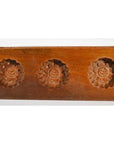 Close-up of dark wood antique Chinese rice mold with five spiral floral cavities.
