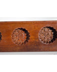 Close-up of dark wood antique Chinese rice mold with five spiral floral cavities.