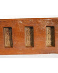 Close-up of antique wooden Chinese rice mold with six rectangular motifs and incised characters, neutral background.