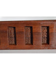 Close-up of brown antique wooden Chinese rice mold with six carved character cavities and curved paddle shape.