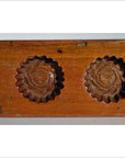 Close-up of antique walnut-finish Chinese rice mold paddle with two round floral cavities, solid wood.