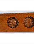 Close-up of walnut-finished antique Chinese rice mold with floral carvings, additional models in background.