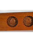 Close-up of walnut-finished antique Chinese rice mold with floral carvings, additional models in background.