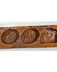 Close-up of a brown antique wooden Chinese rice mold with five cavities, carved star and heart designs.