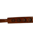 Brown wooden antique Chinese rice mold with long handle and four round rosette cavities, close-up on plain surface.