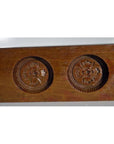 Close-up of antique Chinese rice mold, carved wood, four round seal cavities with calligraphy detail.
