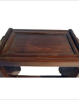 Brown rosewood side table with carved edges and raised border, antique style, seen indoors.