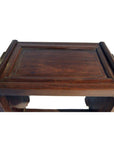 Brown rosewood side table with carved edges and raised border, antique style, seen indoors.