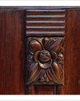 Close-up of dark rosewood side table with floral design and horizontal grooves above the flower.