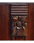Close-up of dark rosewood side table with floral design and horizontal grooves above the flower.