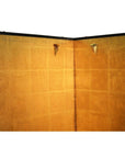 Beige and yellow wall with two small triangular metal fixtures next to an antique Chinese screen.