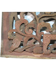 Reddish-brown wood temple carving with intricate floral and leaf designs, close-up.