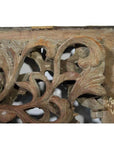 Close-up of weathered wood antique Chinese temple carving with intricate floral and leaf motifs.