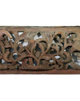 Close-up of a weathered brown wooden panel with intricate floral and leaf carvings, antique Chinese temple art.
