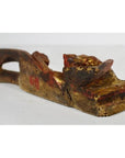 Close-up of worn gold and red wooden reclining figure, antique Chinese temple carving with visible weathering.
