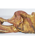 Close-up of gold and red antique Chinese temple carving with bird-like wing and elongated, curved head design.