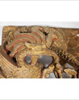 Close-up of gold and red wooden phoenix carving with intricate feather patterns, antique Chinese temple art.
