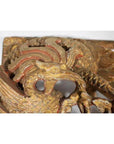 Close-up of gold and red wooden phoenix carving with intricate feather patterns, antique Chinese temple art.