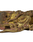 Close-up of antique Chinese temple carving featuring intricate dragon design, weathered wood, and faded gold-red paint.